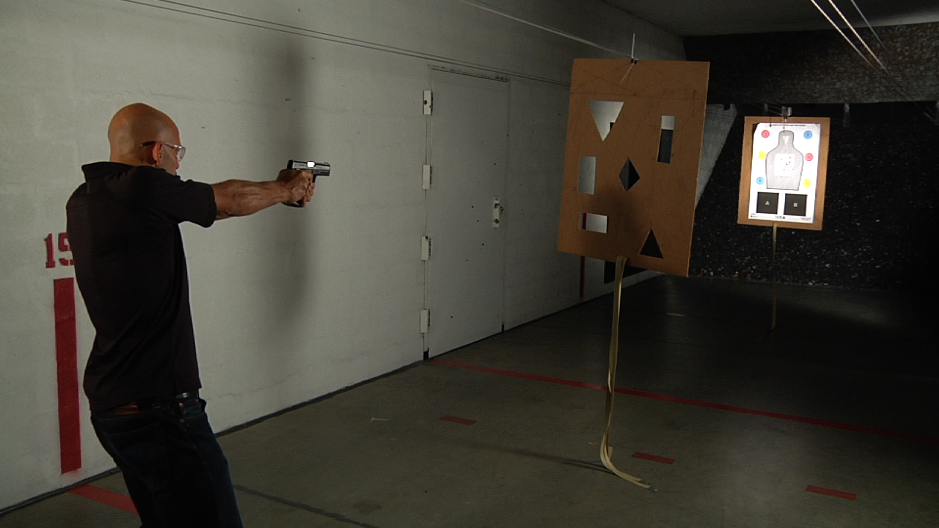 Man aiming a gun at a board with different shapes