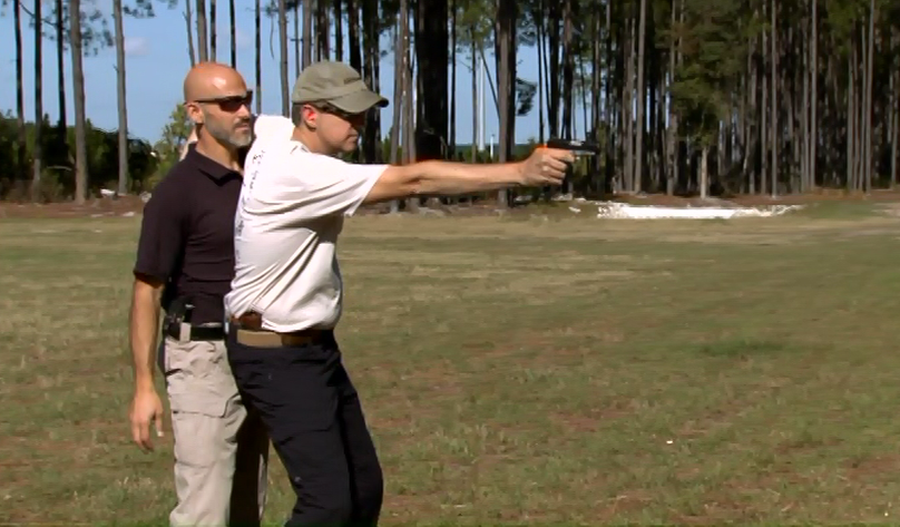 Man aiming a pistol outside