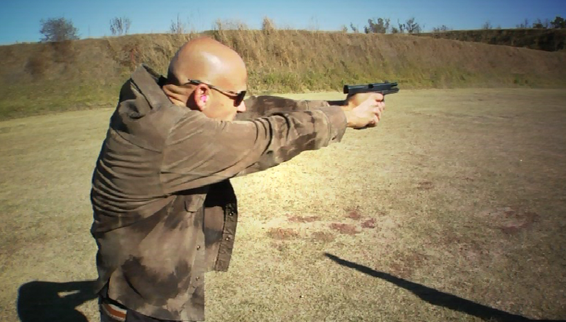 Man outside with a pistol aimed