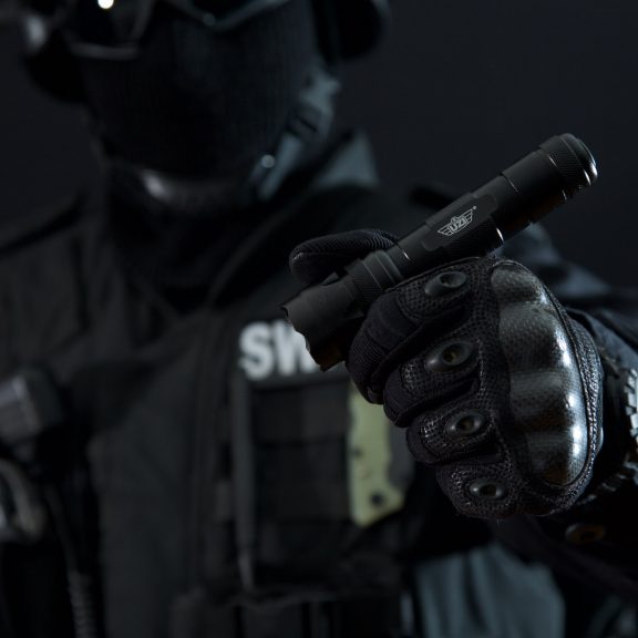 Person wearing gloves holding a tactical style flashlight