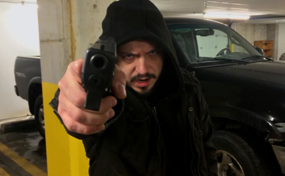 Man pointing a gun in a parking garage
