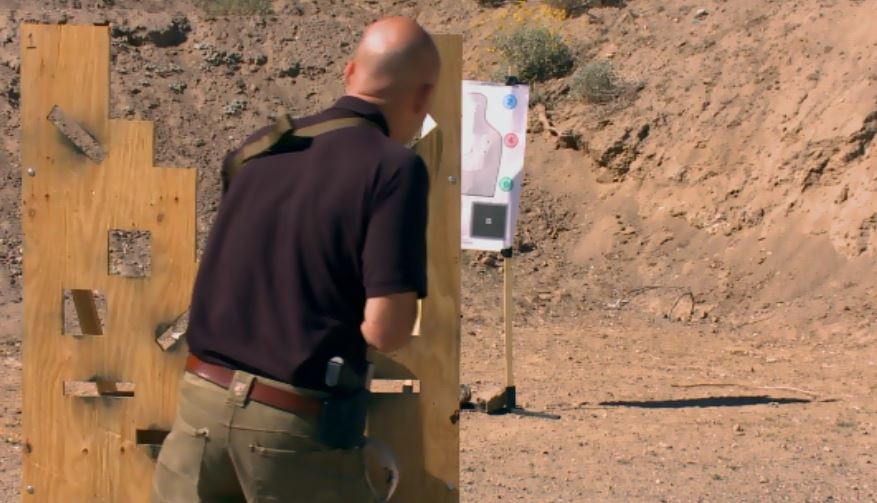 Man aiming around a board at a target