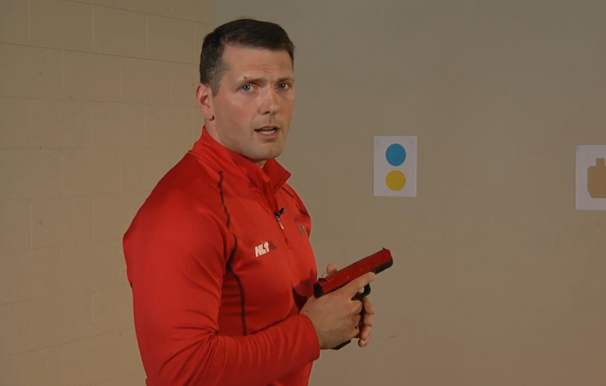 Man wearing red holding a red training pistol