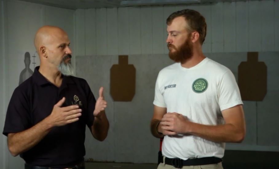 Two men talking in a room with gun targets