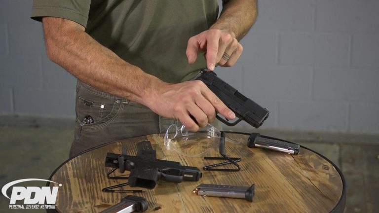 Man holding a gun with gun parts on a table