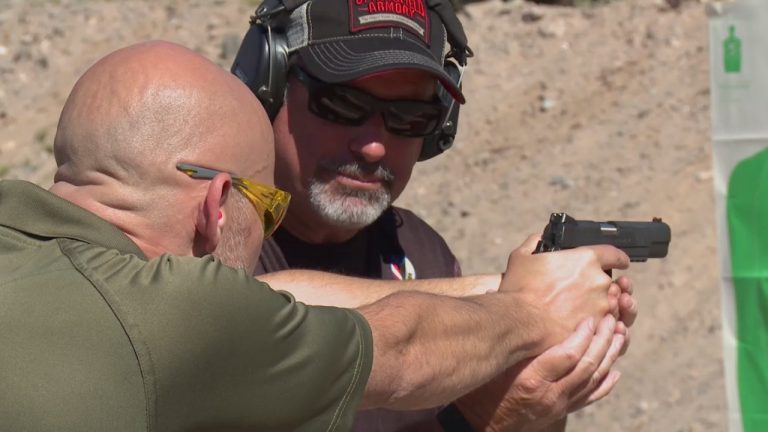 Man helping another man aim a gun