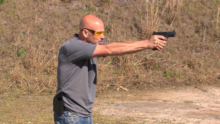 Man wearing eye protection aiming a gun