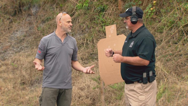 Two men talking outside by a gun target