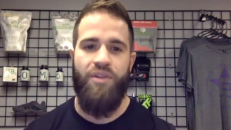 Screenshot of a video of a man talking near merchandise