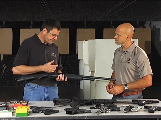 Two men talking with a table of guns