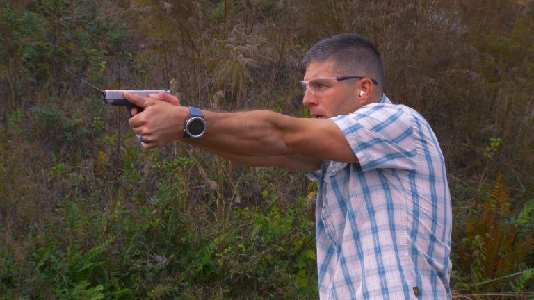 Man wearing safety glasses holding a gun