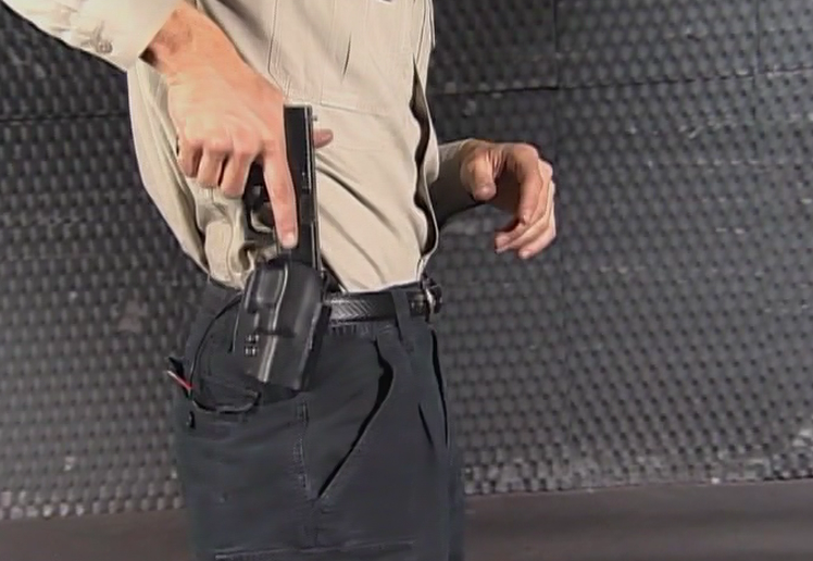 Man putting a gun in a waist holster