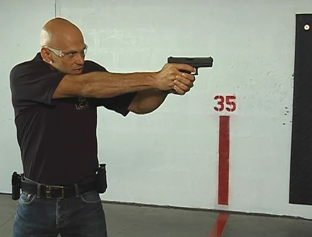 Man holding a gun wearing protective eyewear