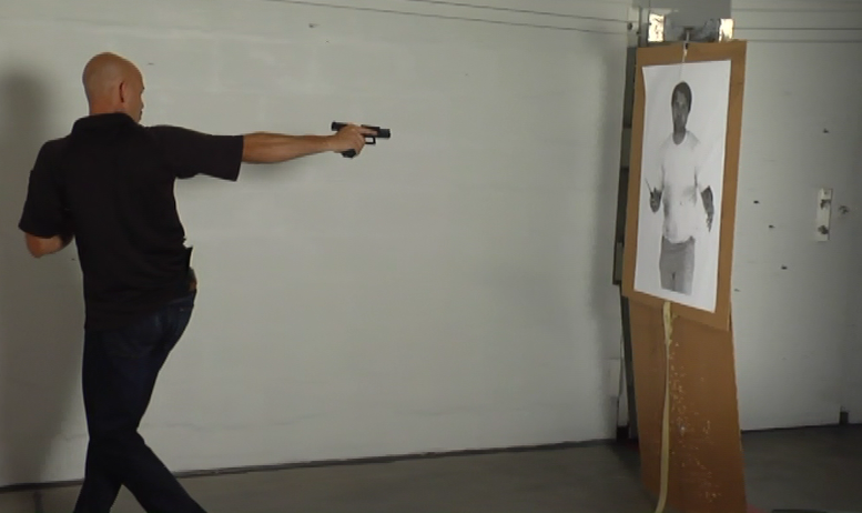 Man turning around aiming a gun at an image of a man