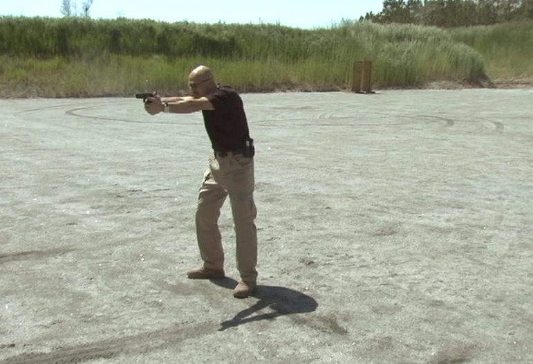 Man outside aiming a gun