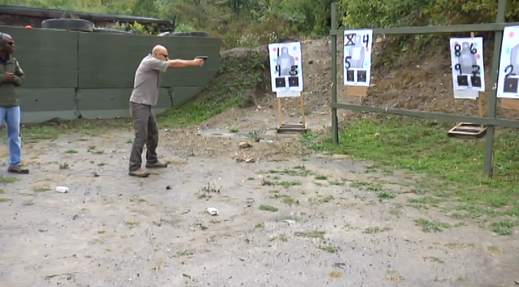 Man aiming at a target outside that has numbers on it