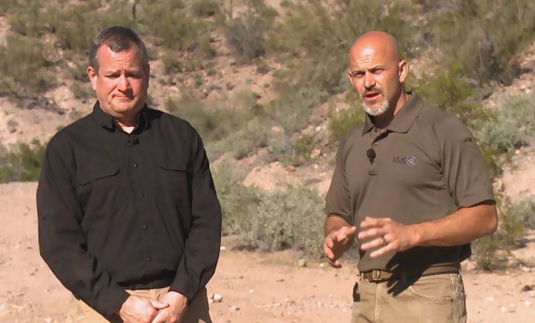 Two men outside in a desert environment talking
