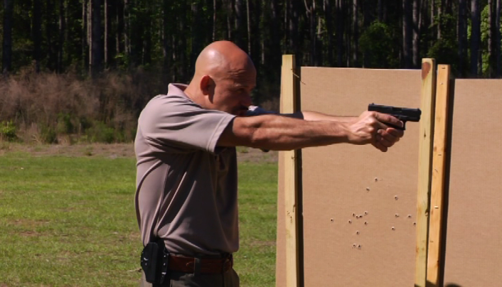 Man aiming a gun outside