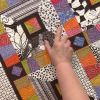 Person pointing to a colorful quilt