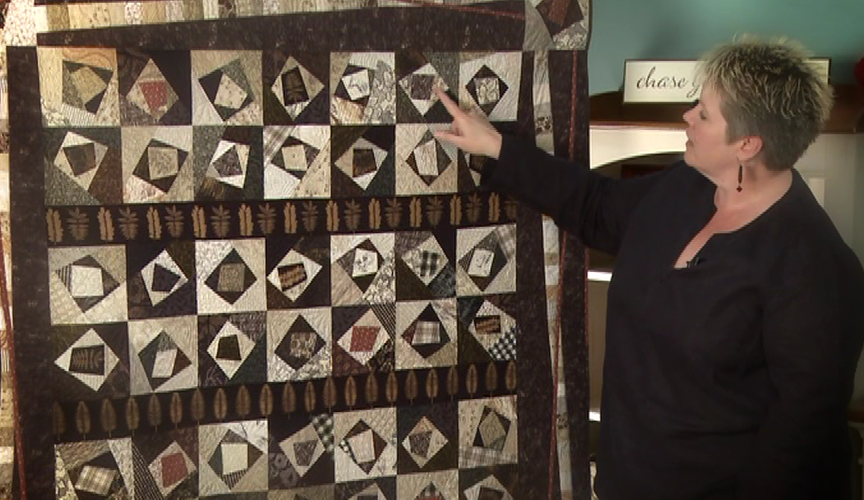 Woman pointing to a large hanging quilt