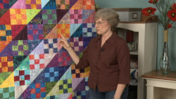 Woman pointing to a hanging quilt