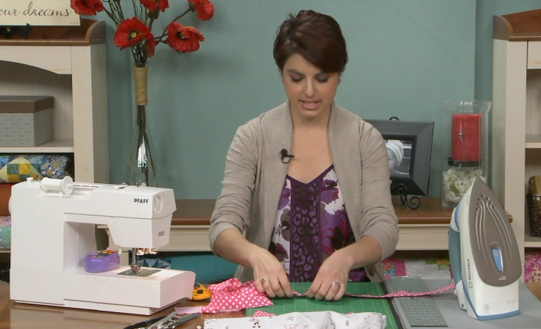 Woman sewing pink and white polka dot fabric