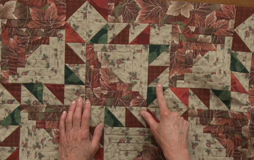 Person pointing to part of a quilt