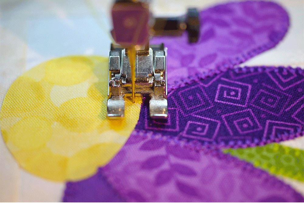 Close up of stitching around a quilted cornflower