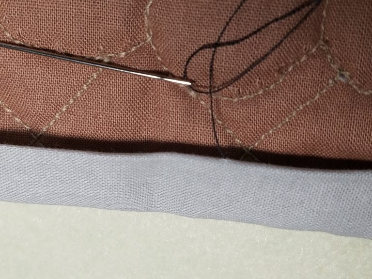 Sewing needle and brown fabric