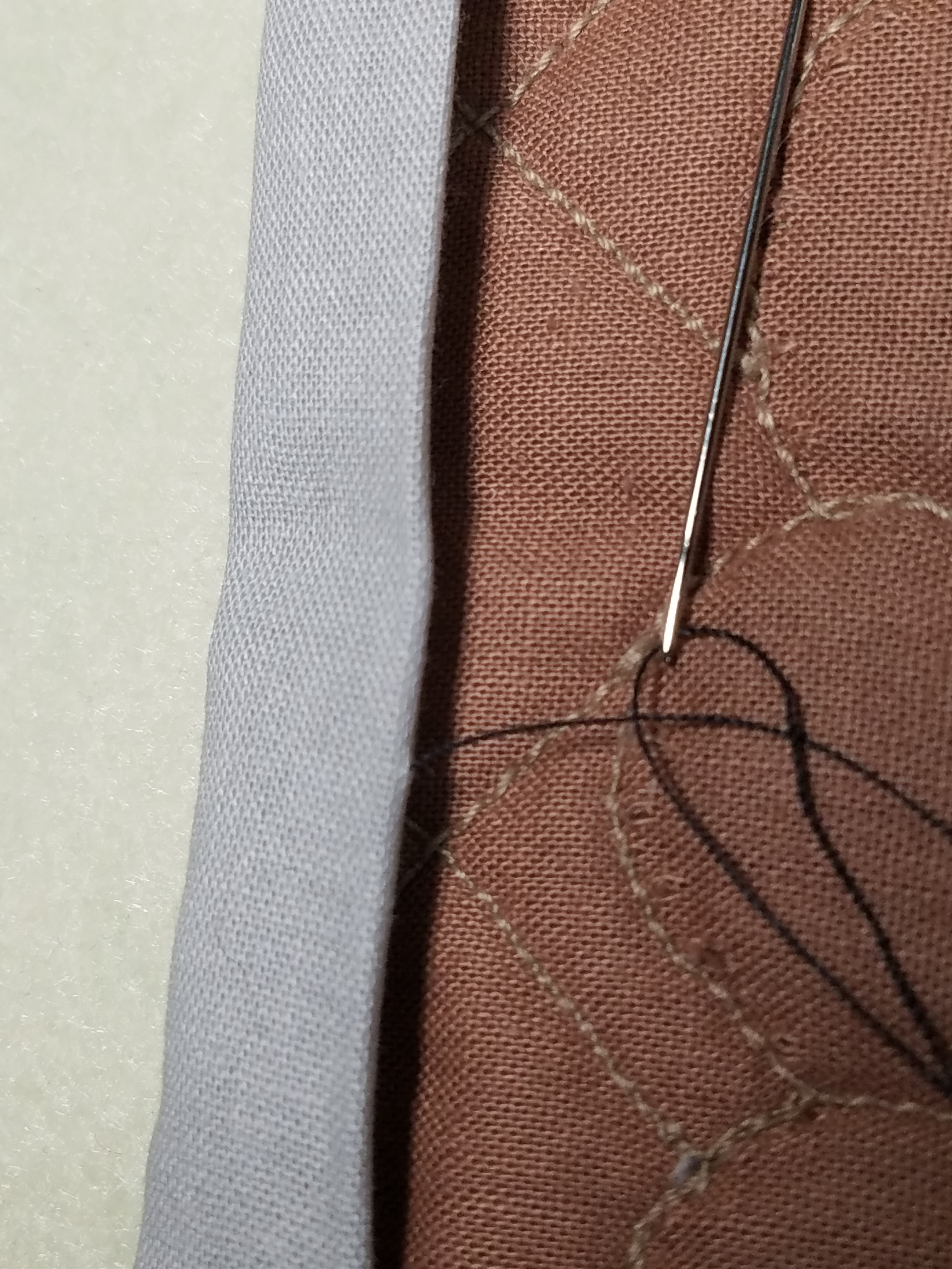 Sewing needle and brown fabric