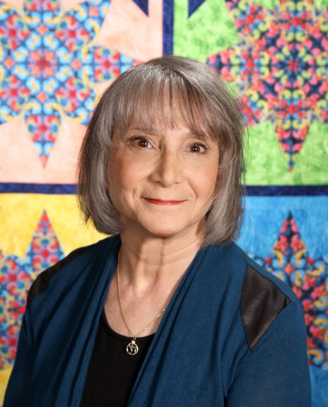 Woman smiling in front of quilts