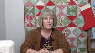 Woman in front of a Christmas quilt