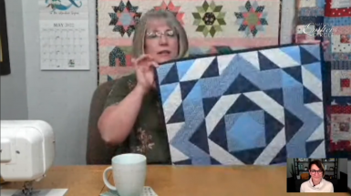 Woman holding up a blue and white quilt