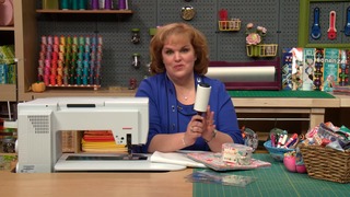 Woman at a quilting table holding a lint roller