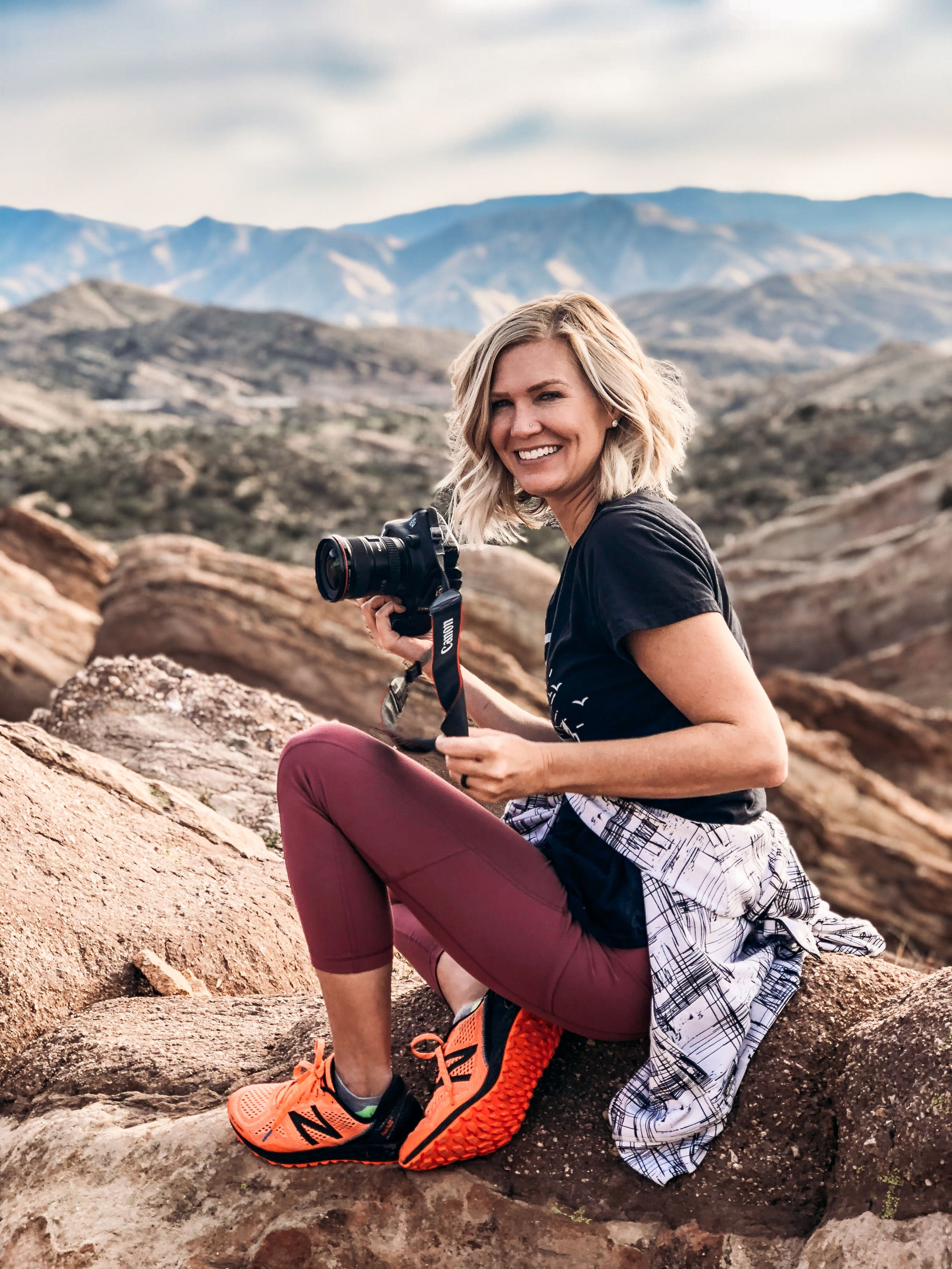 Woman in a canyon with a camera smiling