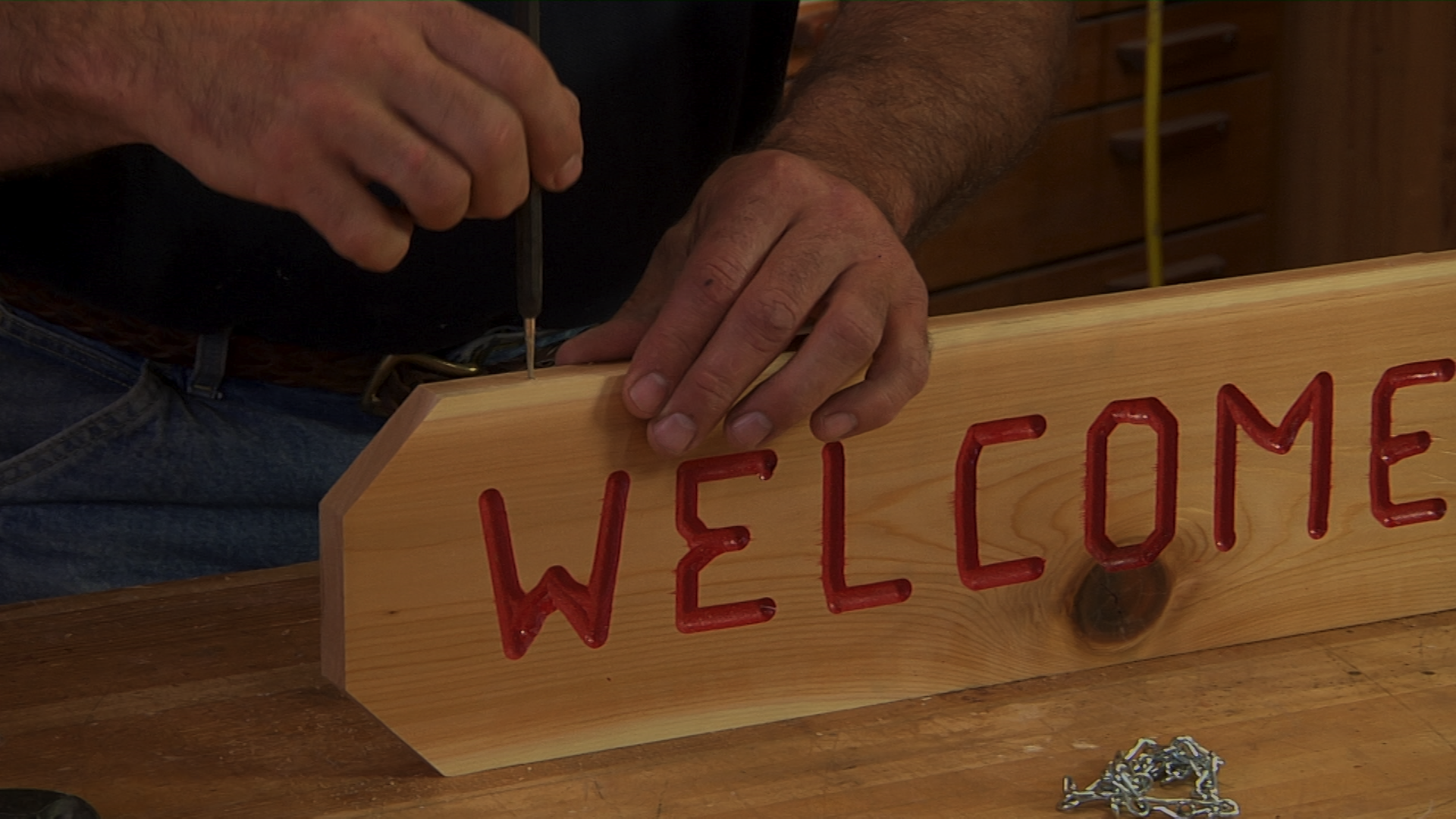 Putting a screw into a wooden welcome sign