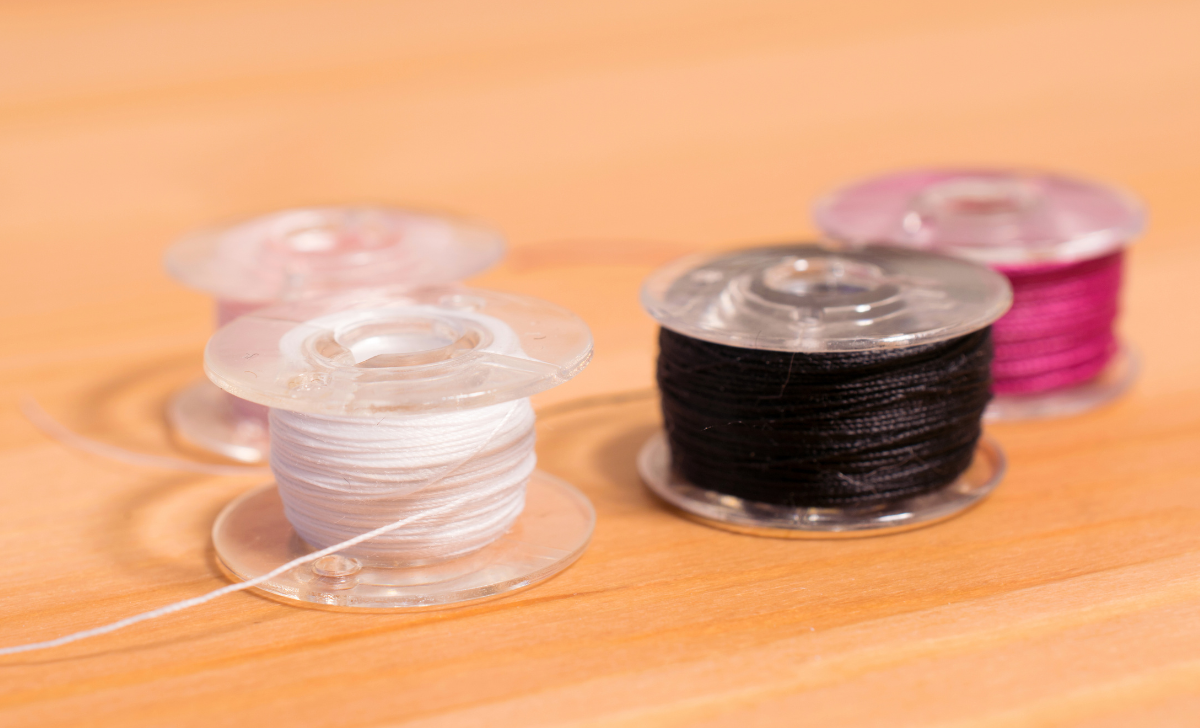 four bobbins sitting on a wooden background