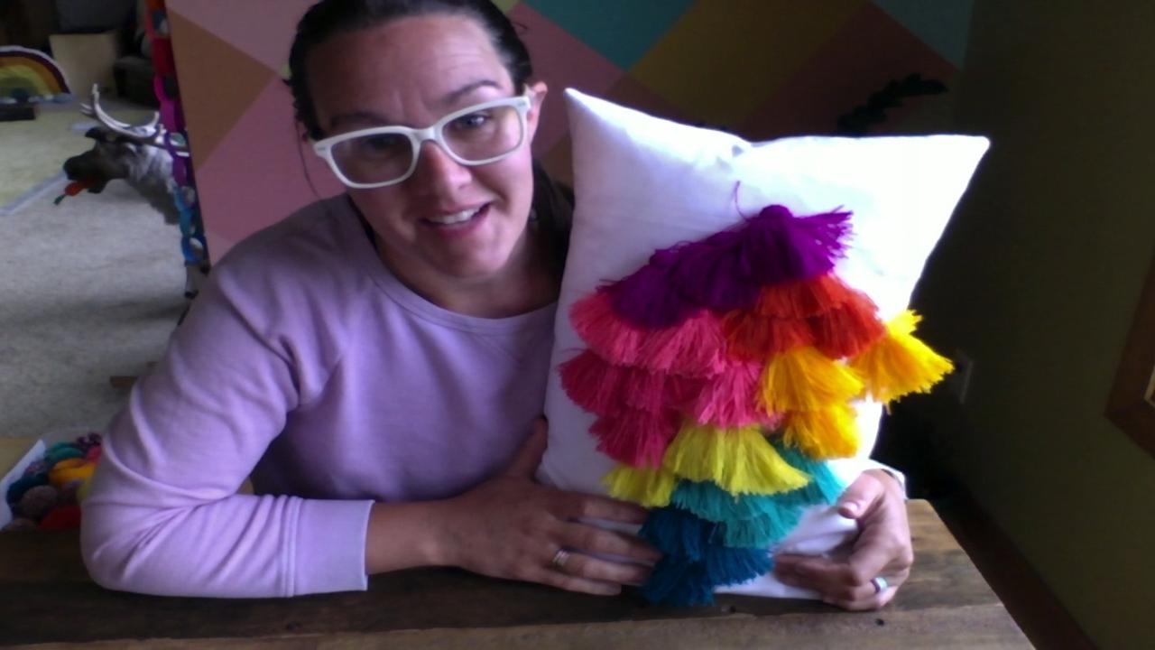 Woman holding a colorful pillow with tassels