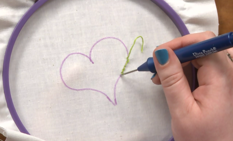 Embroidering a heart with green fabric