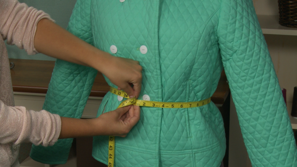 Measuring the waist of a green coat