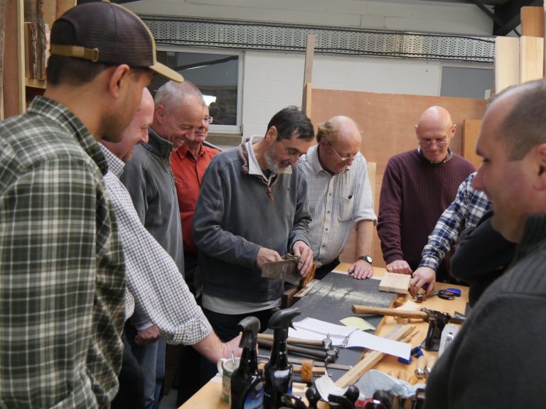 men gathered around a woodworking table