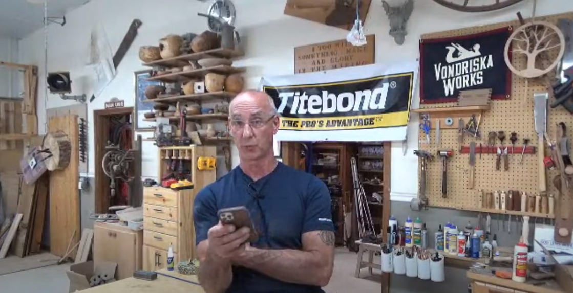 Man in a workshop holding a phone
