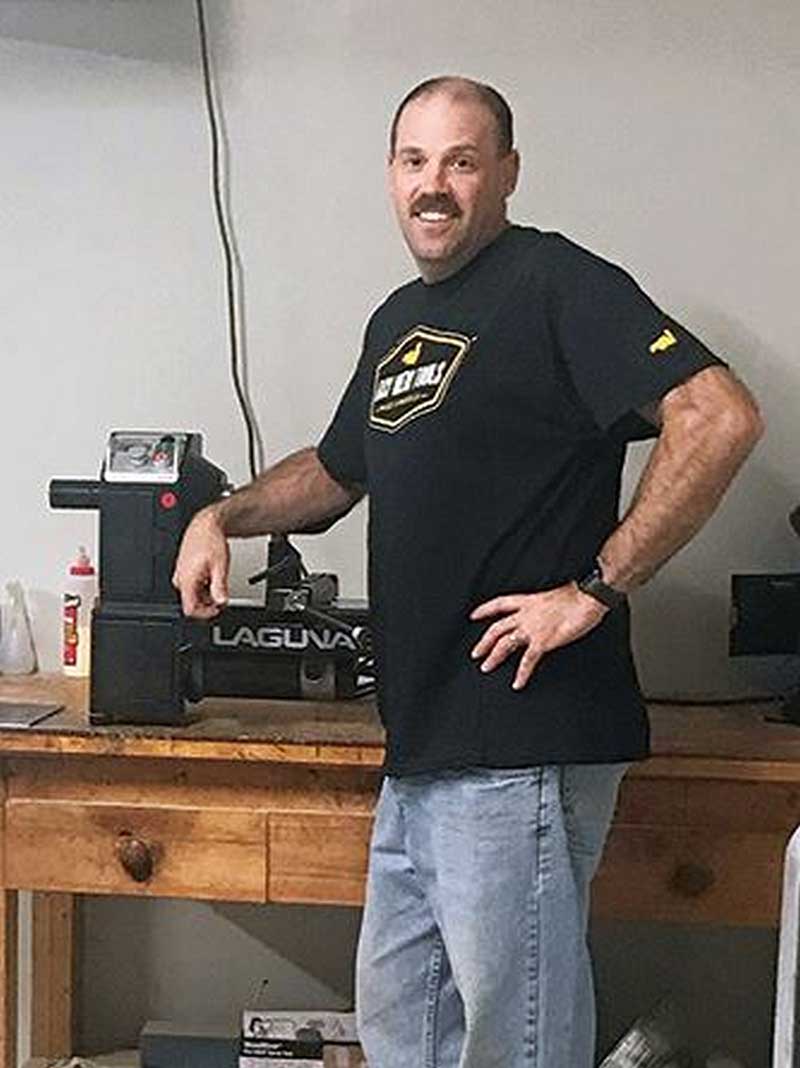 man standing with a wood turning machine