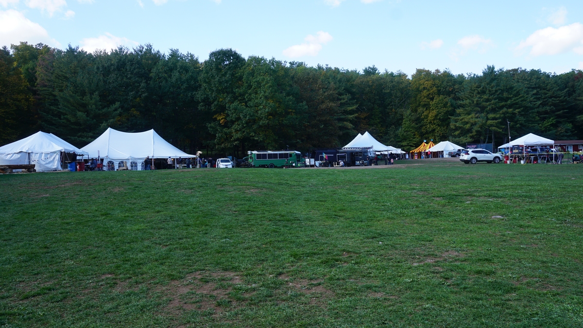 outdoor tents set up in a field near a forest