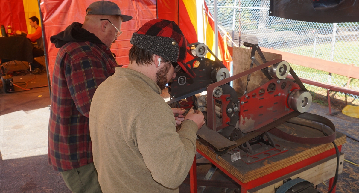 two men outside making knives with machines