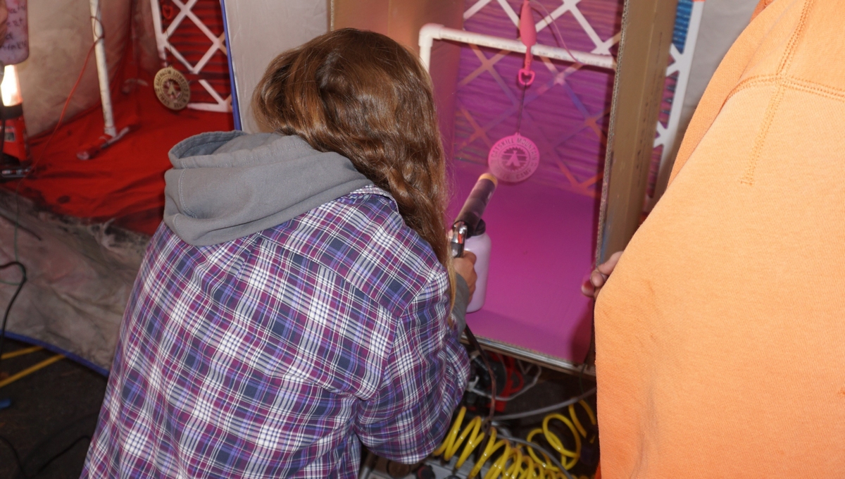 person with a sprayer practicing powder coating