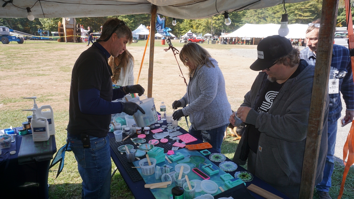 people at an outdoor table under a tent making epoxy projects