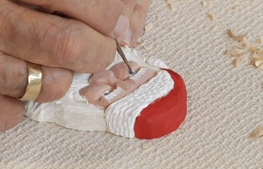 Painting a wooden Santa carving